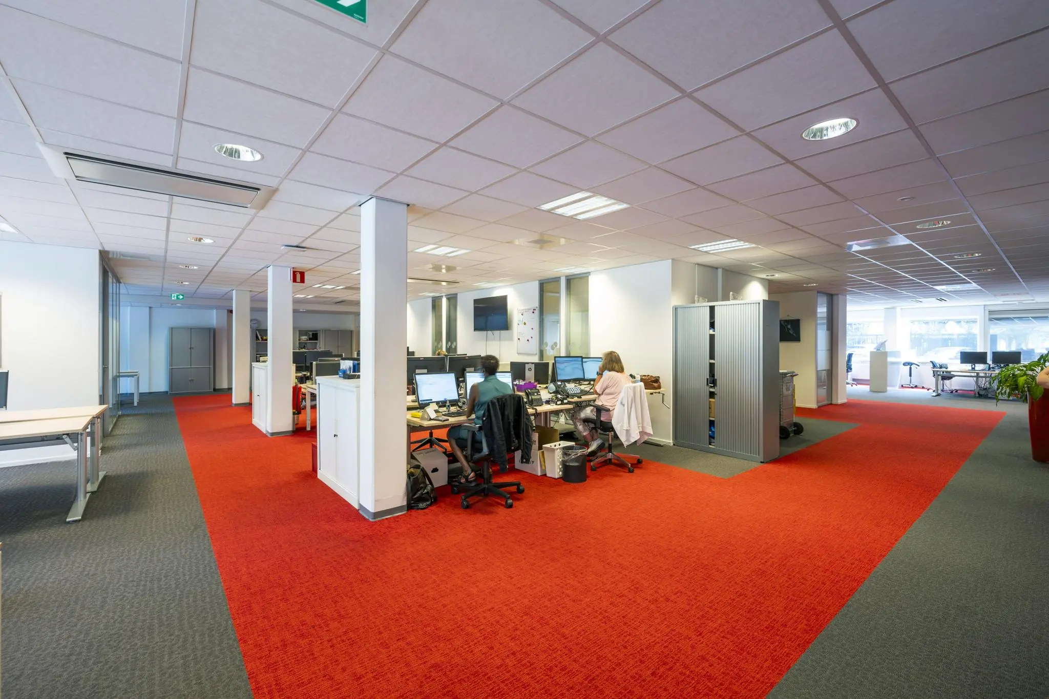 Open kantoorruimte aan de Jan Tooropstraat met werkplekken, computers en twee mensen aan het werk.